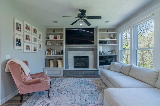 4603 N 111th St, Kansas City, KS 66109 - living room with a textured ceiling, a ceiling fan, wood finished floors, a glass covered fireplace, and built in features