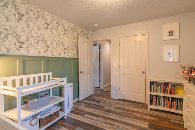 4603 N 111th St, Kansas City, KS 66109 - bedroom featuring dark wood finished floors, wainscoting, a textured ceiling, and a decorative wall