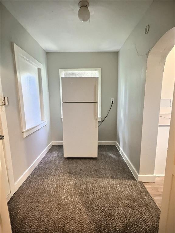 8409 Park Ave, Kansas City, MO 64132 - unfurnished bedroom with freestanding refrigerator, arched walkways, and dark colored carpet