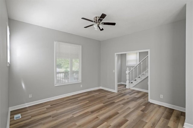 3543 Flora Ave, Kansas City, MO 64109 - unfurnished room featuring stairway, wood finished floors, and a ceiling fan