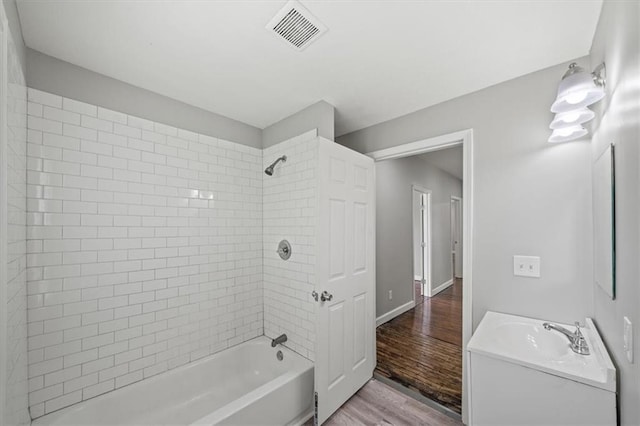 3543 Flora Ave, Kansas City, MO 64109 - bathroom with vanity, shower / washtub combination, and wood finished floors