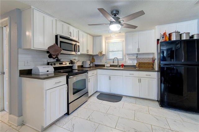 3136 S 8th St, Kansas City, KS 66103 - kitchen with appliances with stainless steel finishes, light marble finish floors, dark countertops, a ceiling fan, and decorative backsplash