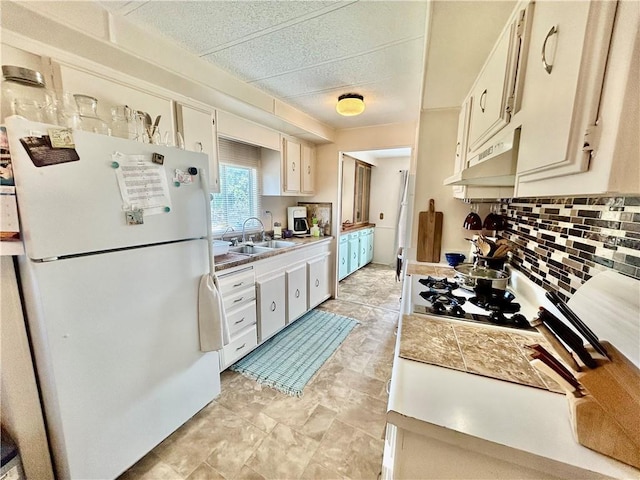 14444 E Quail Rd, Nevada, MO 64772 - kitchen with freestanding refrigerator, under cabinet range hood, backsplash, light countertops, and gas stovetop