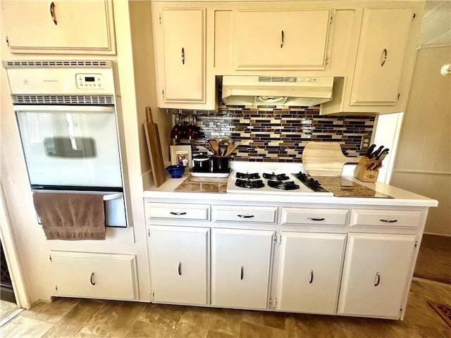 14444 E Quail Rd, Nevada, MO 64772 - kitchen with a warming drawer, under cabinet range hood, white appliances, light countertops, and backsplash