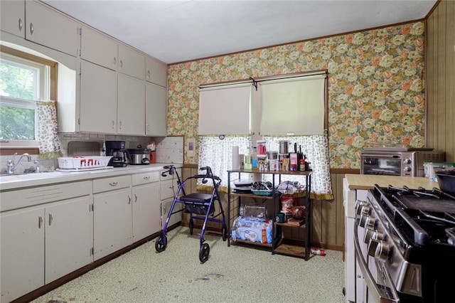 502 N Tennessee St, Iola, KS 66749 - kitchen featuring wallpapered walls, light countertops, stainless steel range with gas stovetop, and white cabinetry