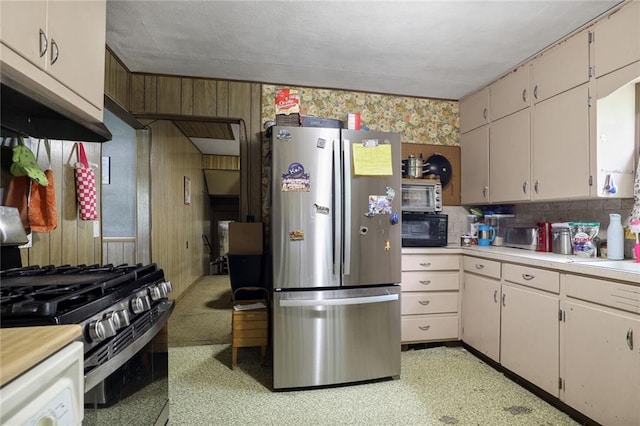 502 N Tennessee St, Iola, KS 66749 - kitchen with freestanding refrigerator, black microwave, light countertops, range with gas cooktop, and wooden walls