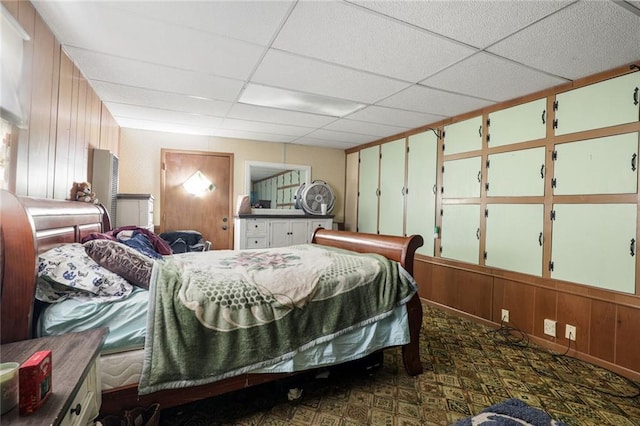 502 N Tennessee St, Iola, KS 66749 - bedroom featuring a paneled ceiling, wood walls, and dark colored carpet
