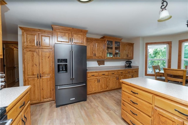 29309 E State Route B, Archie, MO 64725 - kitchen with high quality fridge, light countertops, brown cabinetry, light wood-type flooring, and glass insert cabinets