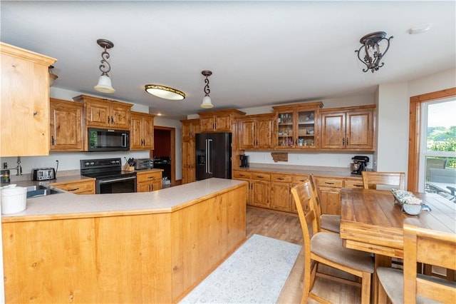 29309 E State Route B, Archie, MO 64725 - kitchen with black appliances, a peninsula, light countertops, pendant lighting, and glass insert cabinets