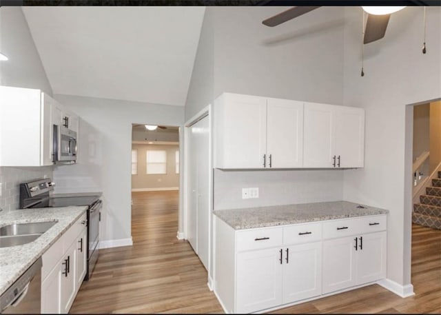 127 E Nelson Cir, Olathe, KS 66061 - kitchen featuring appliances with stainless steel finishes, ceiling fan, light wood-style floors, white cabinets, and high vaulted ceiling