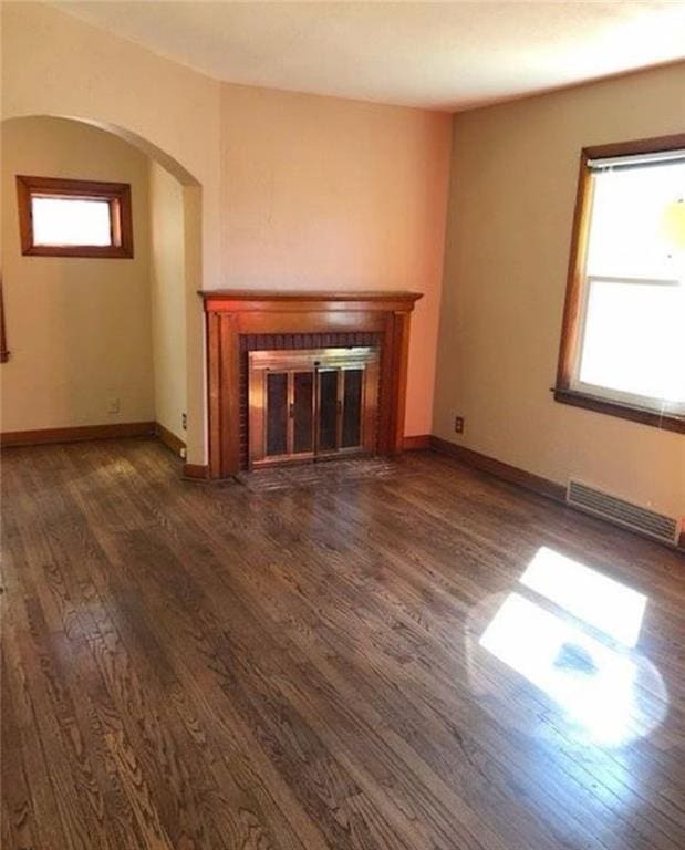 10216 W 60th Ter, Shawnee, KS 66203 - unfurnished living room with a glass covered fireplace, dark wood finished floors, and arched walkways