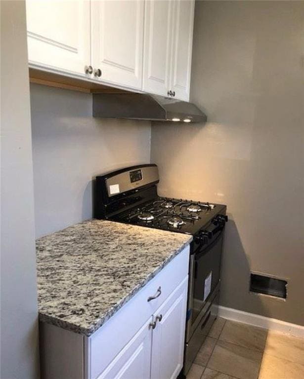 10216 W 60th Ter, Shawnee, KS 66203 - kitchen with range with gas cooktop, under cabinet range hood, white cabinetry, light stone counters, and light tile patterned floors