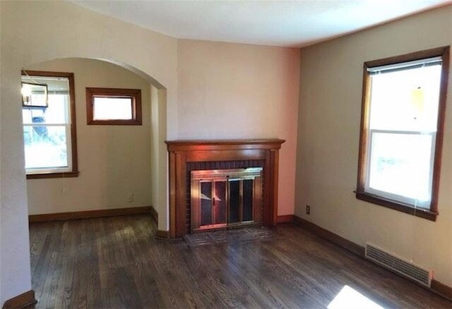 10216 W 60th Ter, Shawnee, KS 66203 - unfurnished living room with a glass covered fireplace, wood finished floors, arched walkways, and plenty of natural light