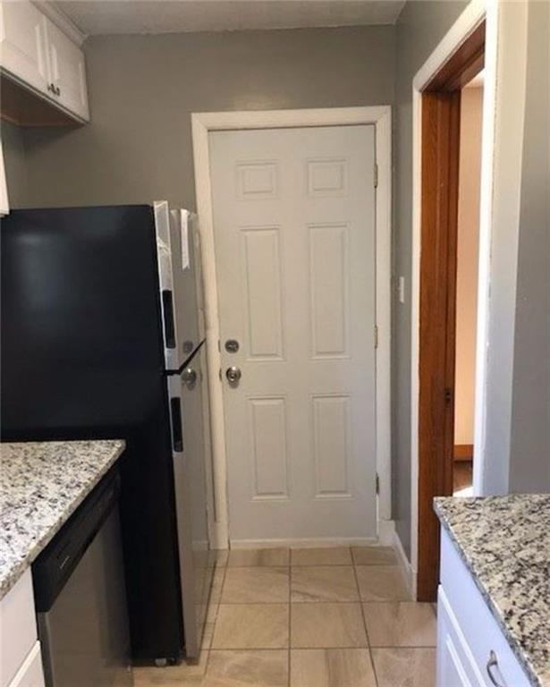 10216 W 60th Ter, Shawnee, KS 66203 - kitchen with appliances with stainless steel finishes, white cabinets, light stone counters, and light tile patterned flooring