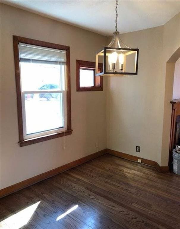 10216 W 60th Ter, Shawnee, KS 66203 - unfurnished dining area featuring dark wood-style floors, arched walkways, and a fireplace