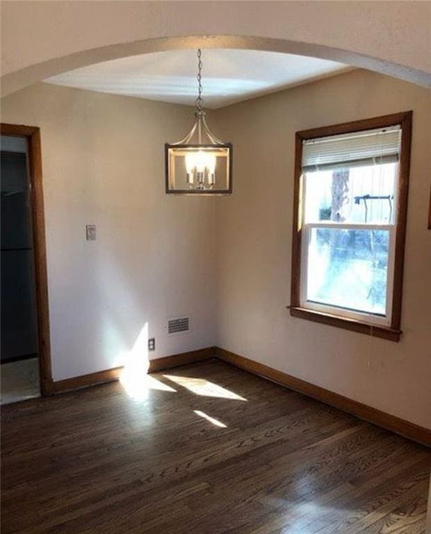 10216 W 60th Ter, Shawnee, KS 66203 - unfurnished room with wood finished floors, a chandelier, and arched walkways