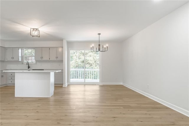1101 SW Kingscross Rd, Blue Springs, MO 64014 - kitchen with a chandelier, light countertops, light wood-type flooring, and a kitchen island