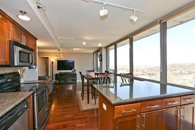 600 E Admiral Blvd Unit 1104, Kansas City, MO 64106 - kitchen featuring track lighting, stainless steel appliances, dark wood-type flooring, dark stone counters, and a wall of windows