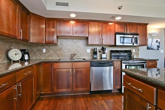 600 E Admiral Blvd Unit 1104, Kansas City, MO 64106 - kitchen featuring appliances with stainless steel finishes, dark stone counters, dark wood-style flooring, decorative backsplash, and recessed lighting