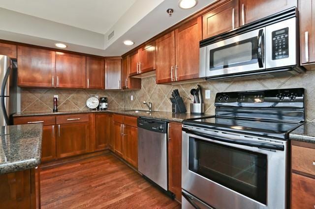 600 E Admiral Blvd Unit 1104, Kansas City, MO 64106 - kitchen with appliances with stainless steel finishes, dark wood-style flooring, dark stone counters, recessed lighting, and backsplash
