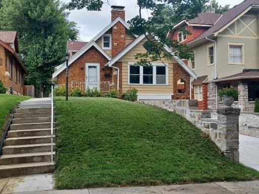 3624 Norledge Ave, Kansas City, MO 64123 - view of front of house featuring a chimney, stairs, a front lawn, and brick siding