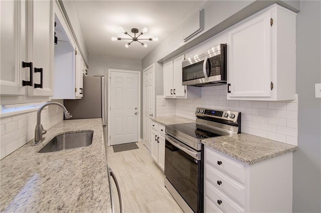 3624 Norledge Ave, Kansas City, MO 64123 - kitchen featuring appliances with stainless steel finishes, decorative backsplash, white cabinets, light stone counters, and a chandelier