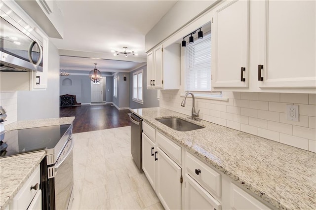 3624 Norledge Ave, Kansas City, MO 64123 - kitchen with appliances with stainless steel finishes, backsplash, white cabinets, light stone counters, and ornamental molding