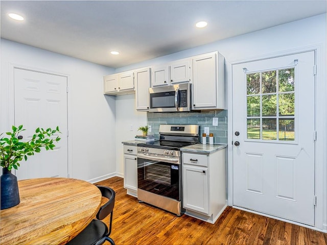 10013 Benson St, Overland Park, KS 66212 - kitchen with stainless steel appliances, dark wood-type flooring, backsplash, white cabinetry, and recessed lighting