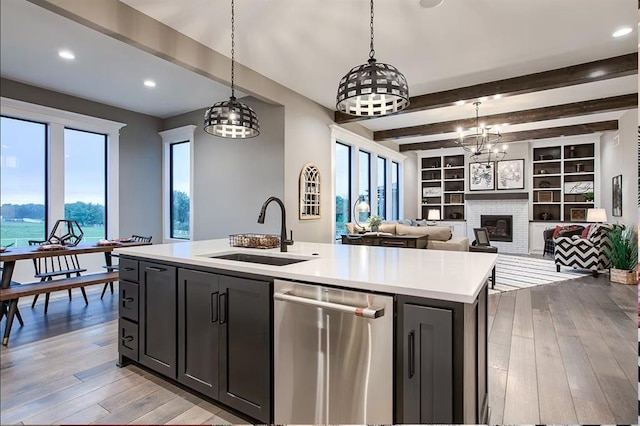 3409 W 187th St, Overland Park, KS 66085 - kitchen with dishwasher, light countertops, an island with sink, a chandelier, and a brick fireplace