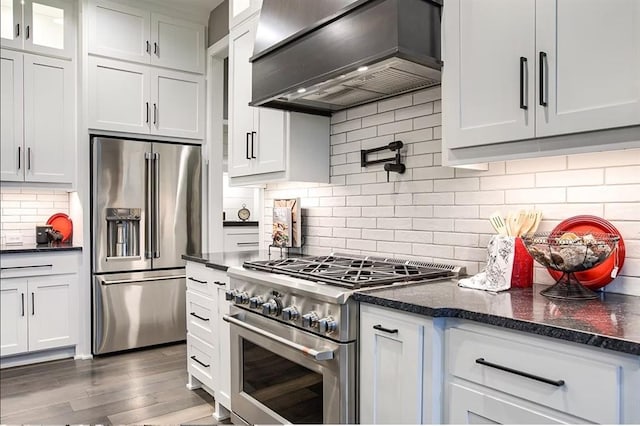 3409 W 187th St, Overland Park, KS 66085 - kitchen featuring high quality appliances, custom range hood, tasteful backsplash, wood finished floors, and glass insert cabinets