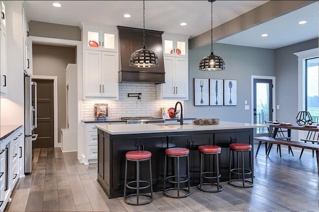 3409 W 187th St, Overland Park, KS 66085 - kitchen featuring hardwood / wood-style flooring, a breakfast bar, backsplash, a kitchen island with sink, and white cabinetry