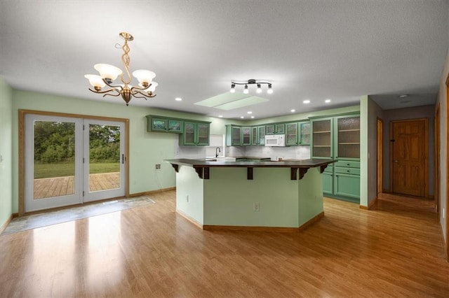 295 E 2300th Rd, Edgerton, KS 66021 - kitchen with green cabinets, white microwave, a kitchen breakfast bar, light wood-style flooring, and a chandelier