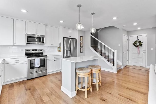 3726 SW Walsh Dr, Lees Summit, MO 64082 - kitchen featuring appliances with stainless steel finishes, light wood finished floors, a center island, white cabinetry, and recessed lighting