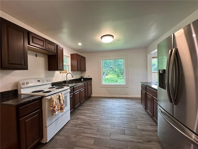 3009 N 33rd St, Kansas City, KS 66104 - kitchen with stainless steel fridge, white range with electric stovetop, dark countertops, dark brown cabinets, and recessed lighting