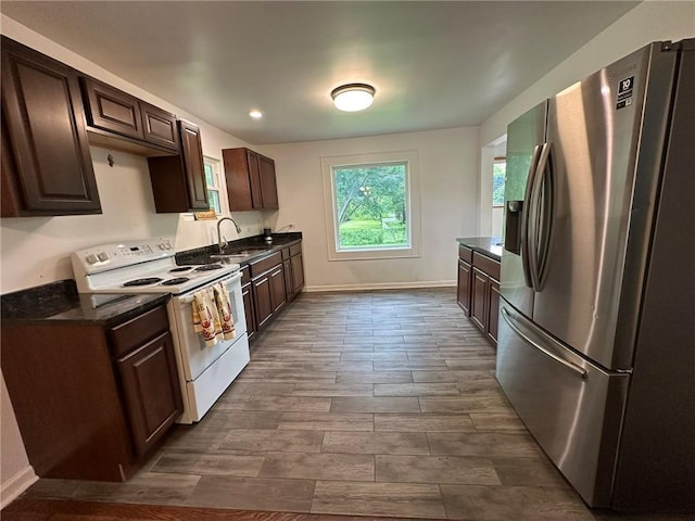 3009 N 33rd St, Kansas City, KS 66104 - kitchen featuring stainless steel fridge, white range with electric stovetop, dark countertops, and dark brown cabinets