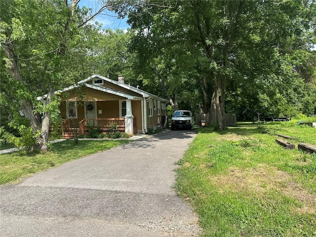 3009 N 33rd St, Kansas City, KS 66104 - bungalow featuring a porch, asphalt driveway, a chimney, and a front yard