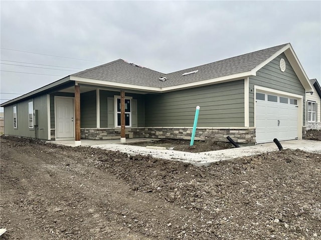 591 W Lanesfield St, Gardner, KS 66030 - view of home's exterior featuring an attached garage, dirt driveway, stone siding, roof with shingles, and a porch