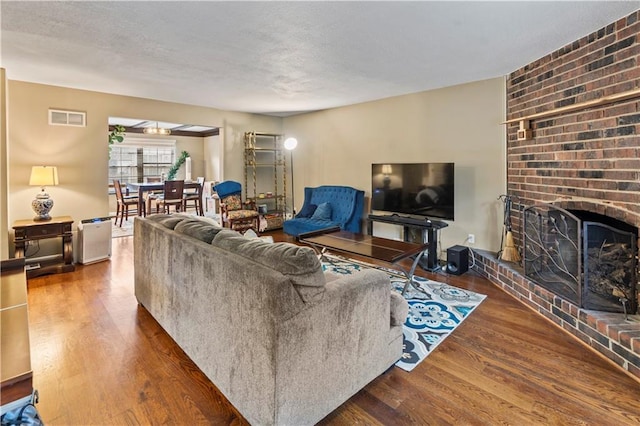 27 W Bannister Rd, Kansas City, MO 64114 - living room with wood finished floors, a brick fireplace, and a textured ceiling