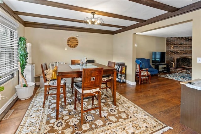 27 W Bannister Rd, Kansas City, MO 64114 - dining room featuring wood finished floors, beam ceiling, a brick fireplace, and a chandelier