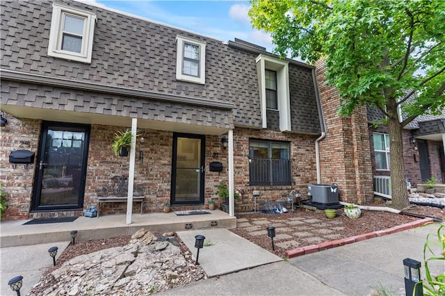 27 W Bannister Rd, Kansas City, MO 64114 - view of front of home featuring mansard roof, roof with shingles, covered porch, and brick siding