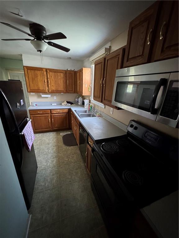 5647 Wayne Ave, Kansas City, MO 64110 - kitchen with stainless steel microwave, electric range, freestanding refrigerator, dishwashing machine, and ceiling fan