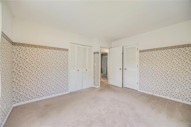 561 SW County Road O, Holden, MO 64040 - unfurnished bedroom featuring wallpapered walls, carpet flooring, and two closets