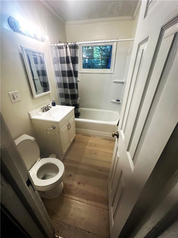 2209 E 72nd St, Kansas City, MO 64132 - bathroom with crown molding, vanity, shower / bath combination with curtain, and hardwood / wood-style flooring