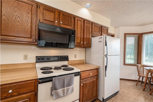 596 E 1732nd Rd, Baldwin City, KS 66006 - kitchen featuring white appliances, light countertops, brown cabinetry, and a textured ceiling