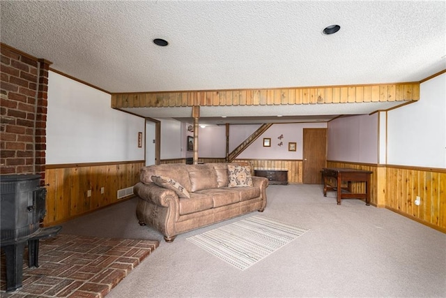 596 E 1732nd Rd, Baldwin City, KS 66006 - carpeted living room with a wood stove, a wainscoted wall, wood walls, and a textured ceiling