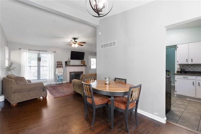 1101 Anderson St, Warrensburg, MO 64093 - dining space with a fireplace, dark wood finished floors, ceiling fan, and a chandelier