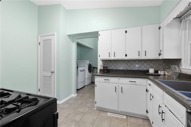 1101 Anderson St, Warrensburg, MO 64093 - kitchen featuring separate washer and dryer, black range with gas cooktop, dark countertops, white cabinets, and backsplash