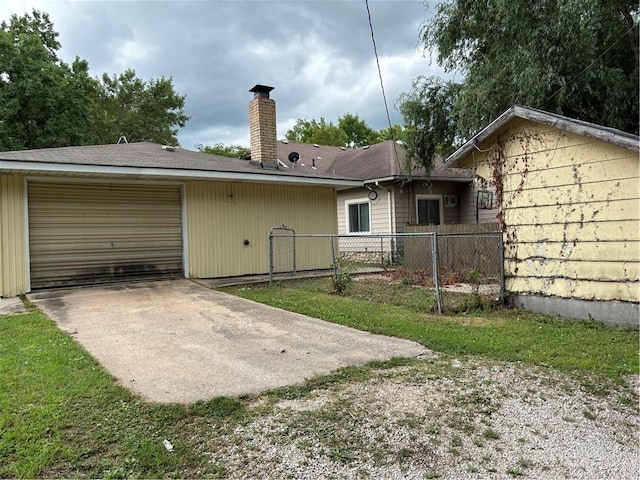 420 S Walnut St, Iola, KS 66749 - back of house featuring a garage, a chimney, and driveway