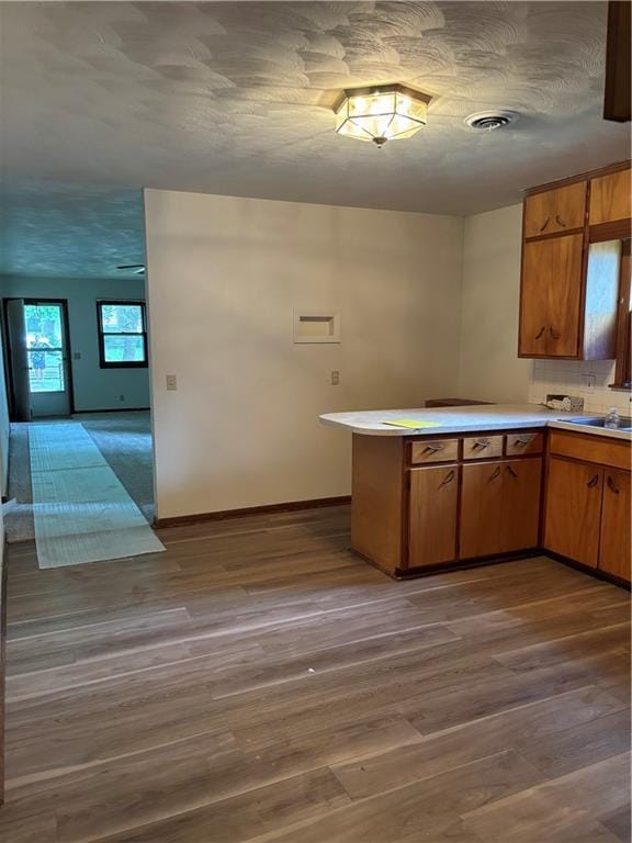 420 S Walnut St, Iola, KS 66749 - kitchen with wood finished floors, light countertops, a peninsula, and brown cabinetry