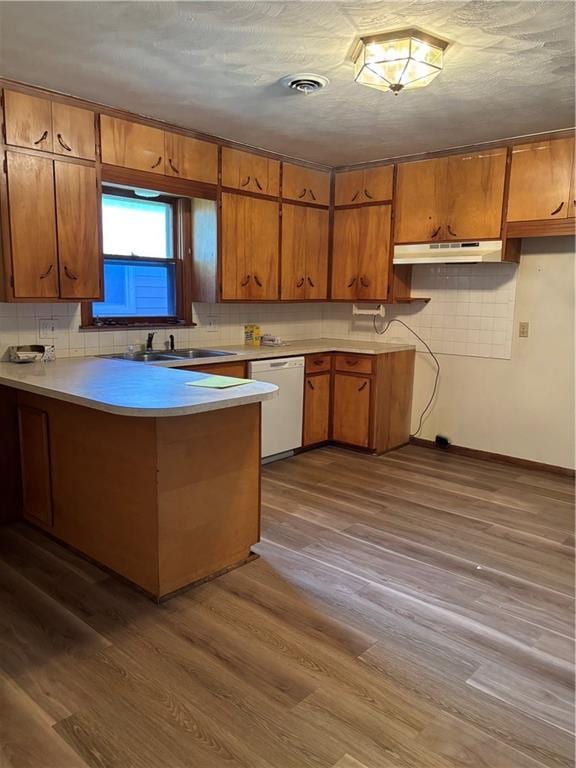 420 S Walnut St, Iola, KS 66749 - kitchen with dishwasher, under cabinet range hood, brown cabinets, a peninsula, and wood finished floors